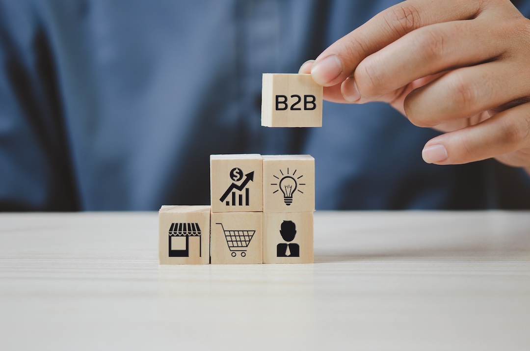 Hand put wooden cubes with B2B Business to Business icons and symbols on table and copy space.Business concepts.